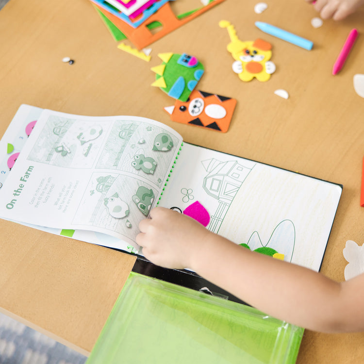 A kid playing with The Melissa & Doug On the Go Felt Friends Craft Activity Set With 188 Felt Stickers