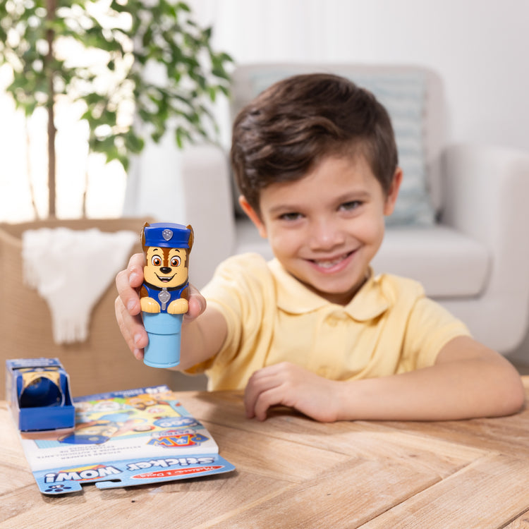 A kid playing with The Melissa & Doug Sticker WOW!™ 24-Page Activity Pad and Sticker Stamper, 300 Stickers, Arts and Crafts Fidget Toy Collectible Character – PAW Patrol Chase
