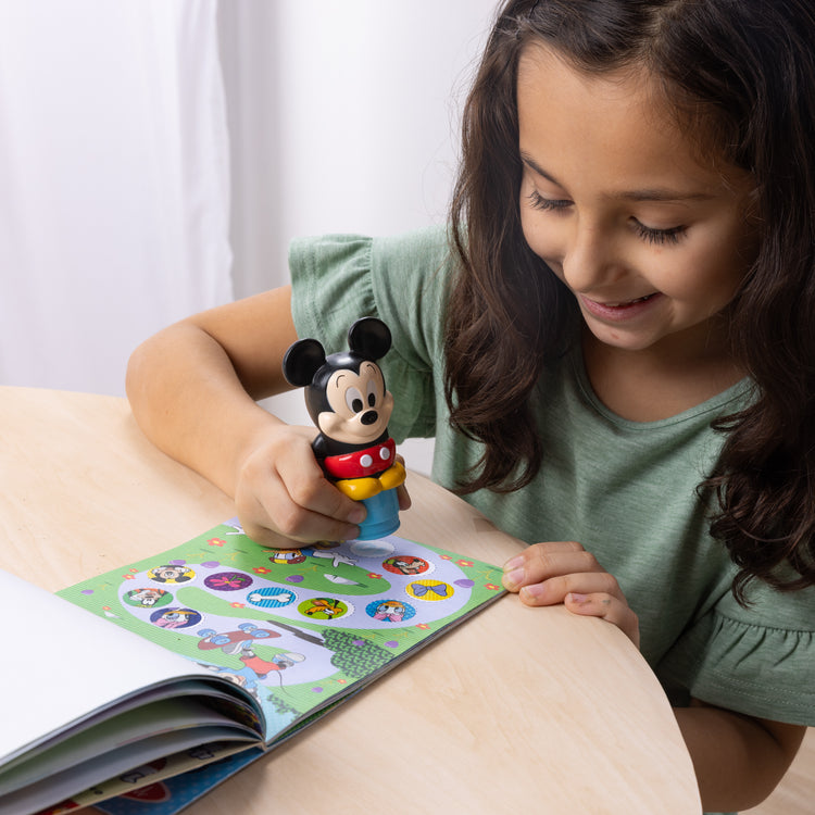A kid playing with The Melissa & Doug Sticker WOW!™ Disney Mickey Mouse Bundle: 24-Page Activity Pad, Sticker Stamper, 500 Stickers, Mini Pad, Arts and Crafts Fidget Toy Collectible Character