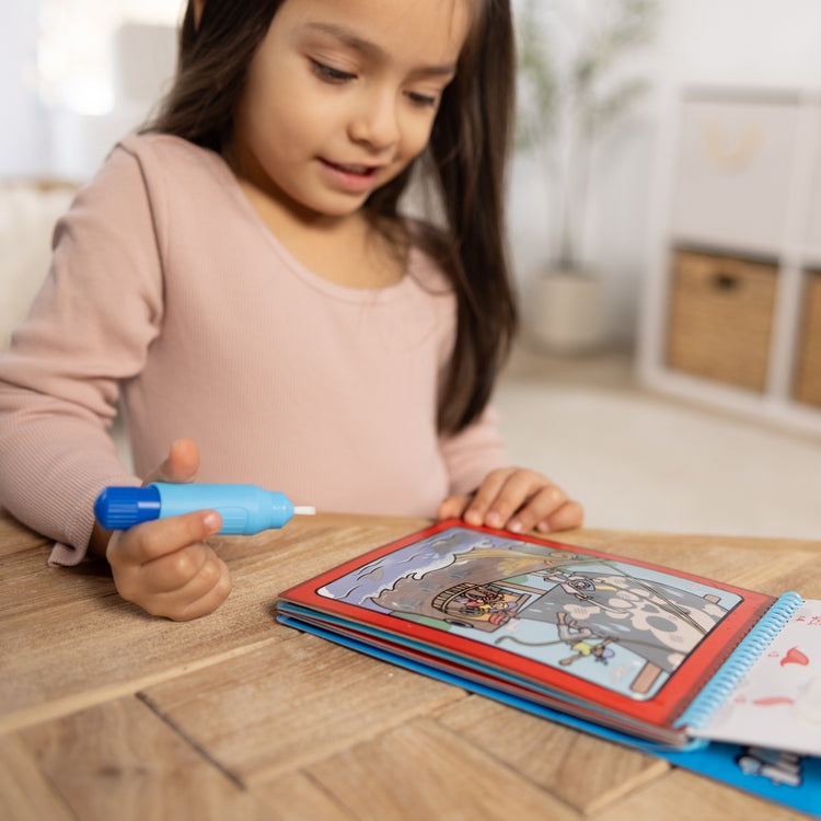 A kid playing with The Melissa & Doug Water WOW! 3-Pack – Dinosaur, Adventure, Space Water-Reveal Travel Activity Pads