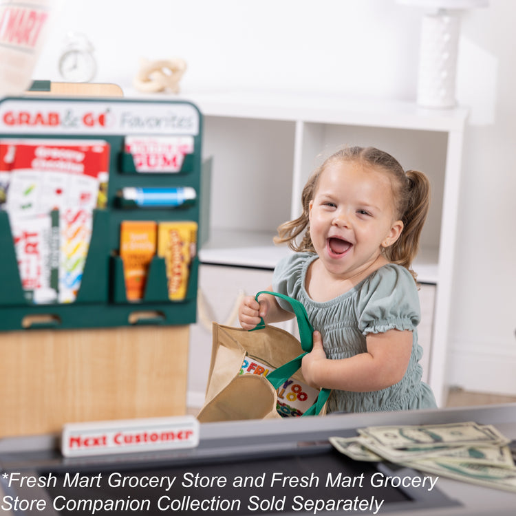 A kid playing with The Melissa & Doug Freestanding Wooden Fresh Mart Grocery Store