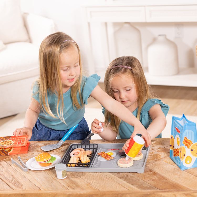 A kid playing with The Melissa & Doug Flip & Fry Grill Play Set with Water WOW!® Color Reveal Play Food Preschool Toy Ages 3+