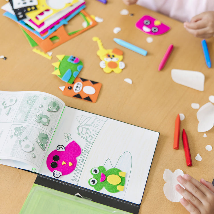 A kid playing with The Melissa & Doug On the Go Felt Friends Craft Activity Set With 188 Felt Stickers