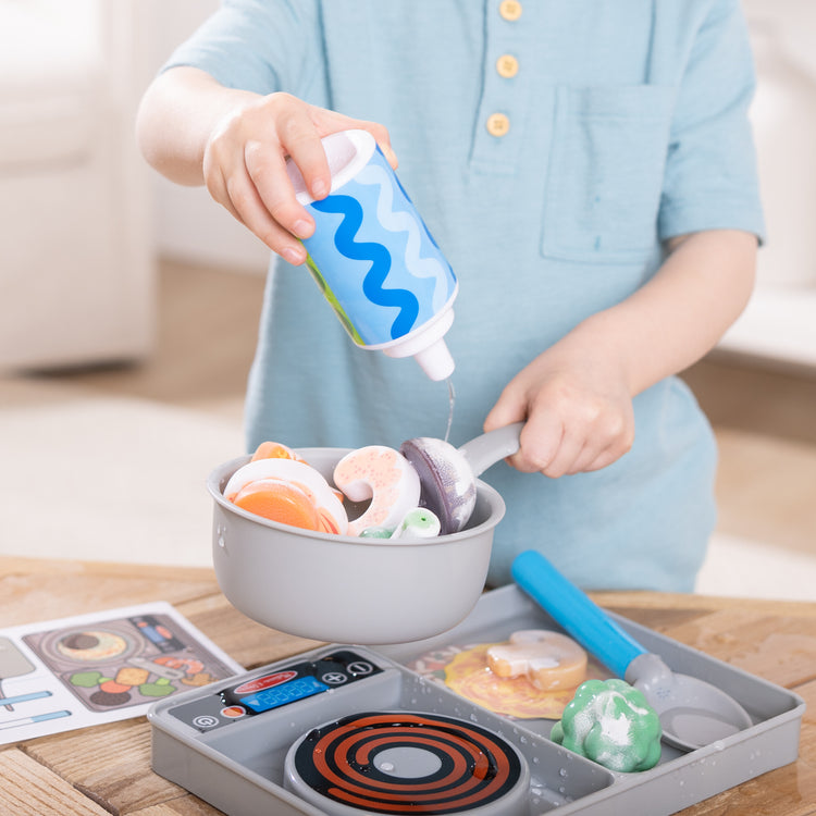 A kid playing with The Melissa & Doug Simmer & Stir Stovetop Play Set with Water WOW!® Color Reveal Play Food Preschool Toy Ages 3+