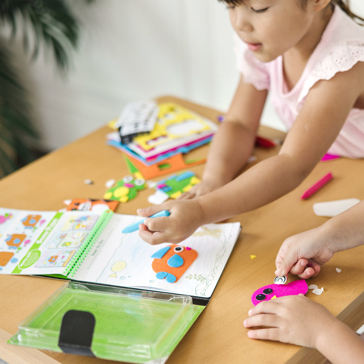 A kid playing with The Melissa & Doug On the Go Felt Friends Craft Activity Set With 188 Felt Stickers