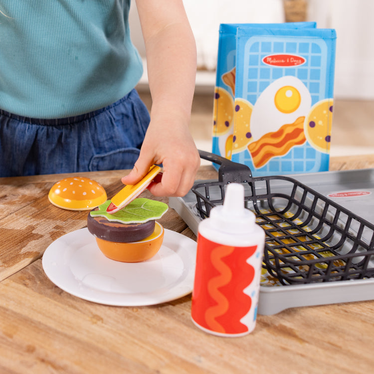 A kid playing with The Melissa & Doug Flip & Fry Grill Play Set with Water WOW!® Color Reveal Play Food Preschool Toy Ages 3+