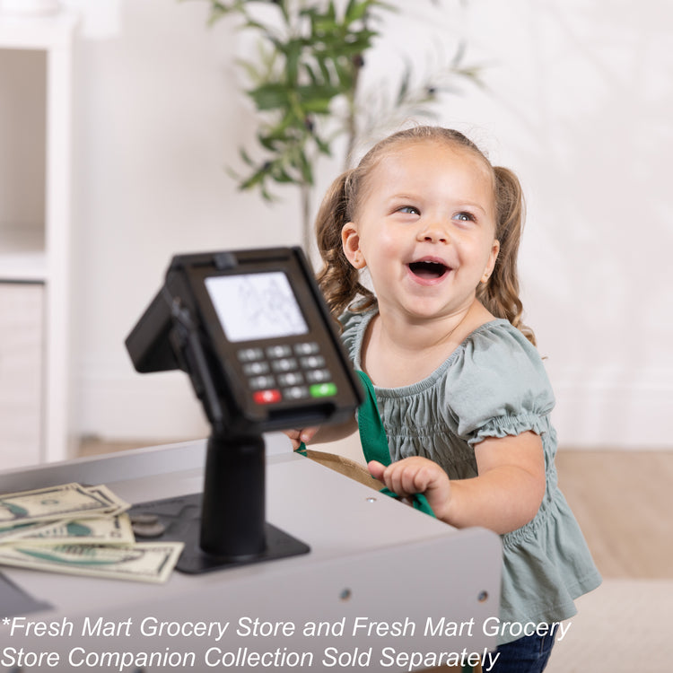 A kid playing with The Melissa & Doug Freestanding Wooden Fresh Mart Grocery Store