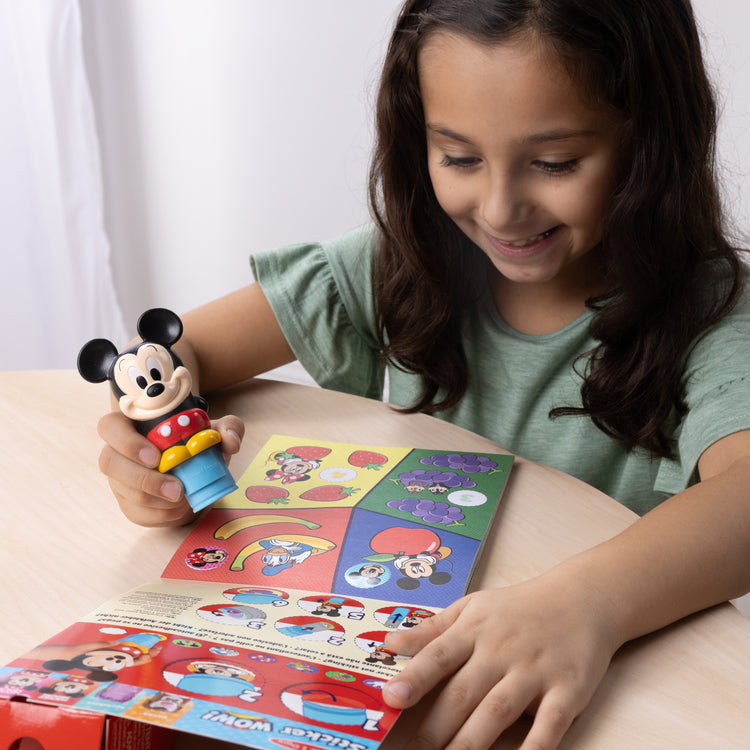 A kid playing with The Melissa & Doug Sticker WOW!™ Disney Mickey Mouse Bundle: 24-Page Activity Pad, Sticker Stamper, 500 Stickers, Mini Pad, Arts and Crafts Fidget Toy Collectible Character