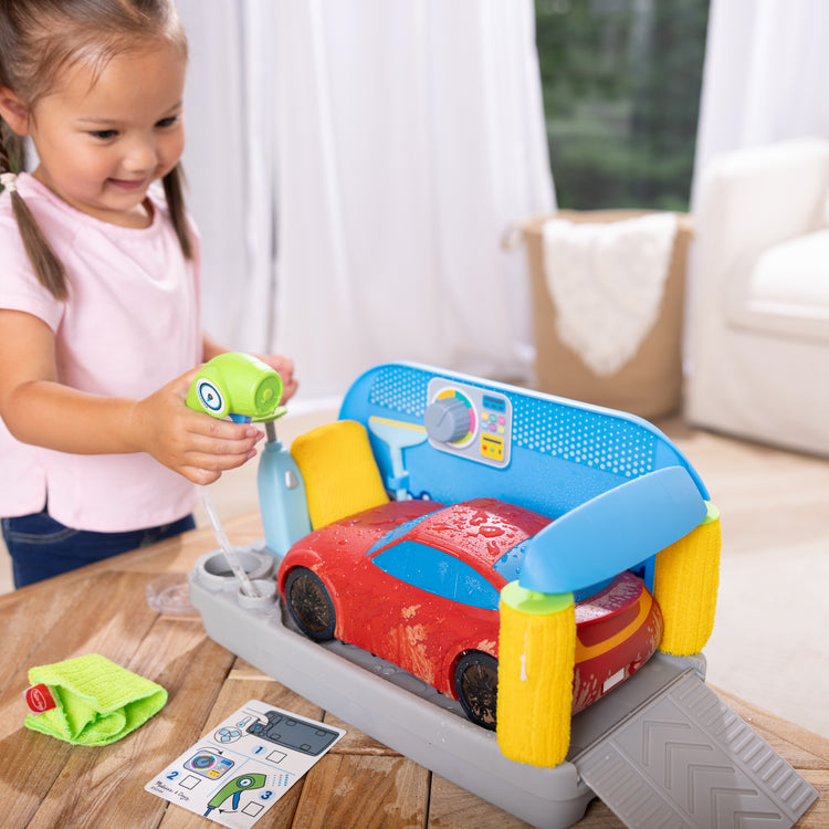 A kid playing with The Melissa & Doug Spray & Shine Car Wash Color-Changing Water Toy Play Set Boys and Girls 3+