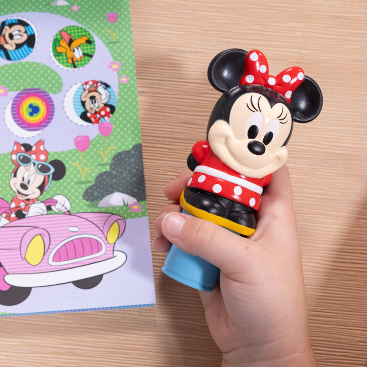 A kid playing with The Melissa & Doug Sticker WOW!™ Disney Minnie Mouse Bundle: 24-Page Activity Pad, Sticker Stamper, 500 Stickers, Mini Pad, Arts and Crafts Fidget Toy Collectible Character