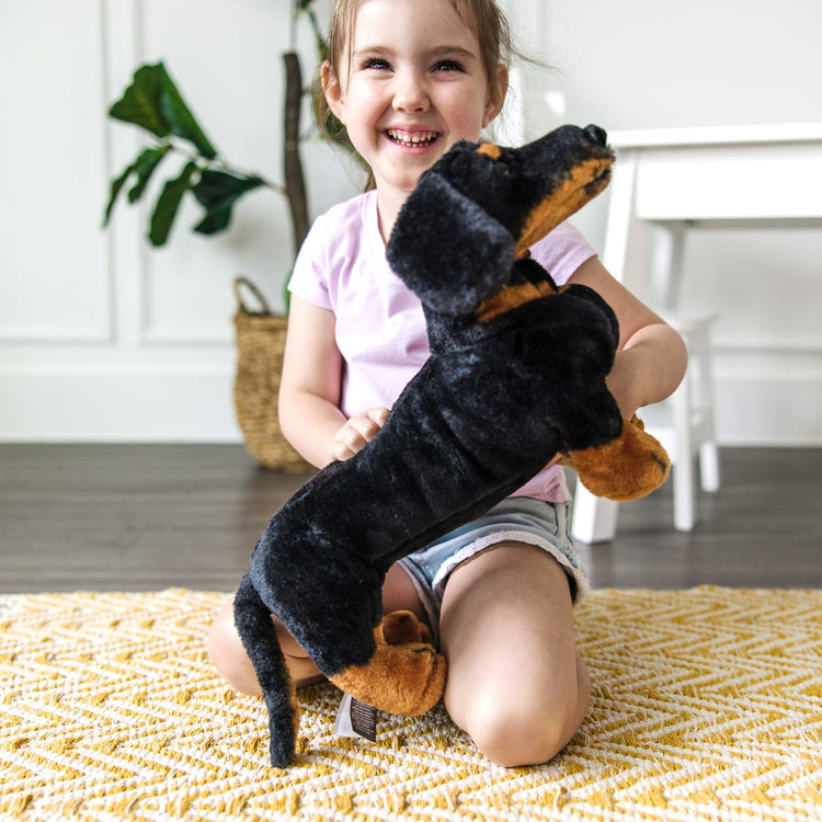 A kid playing with the Melissa & Doug Giant Dachshund - Lifelike Stuffed Animal Dog