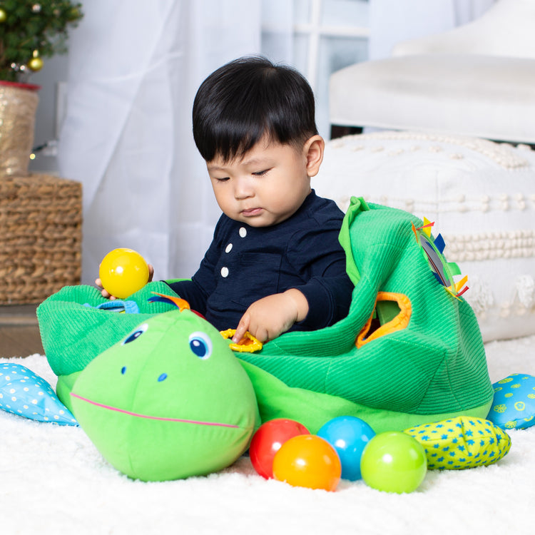 A kid playing with The Melissa & Doug K's Kids Turtle Ball Pit With 60 Balls