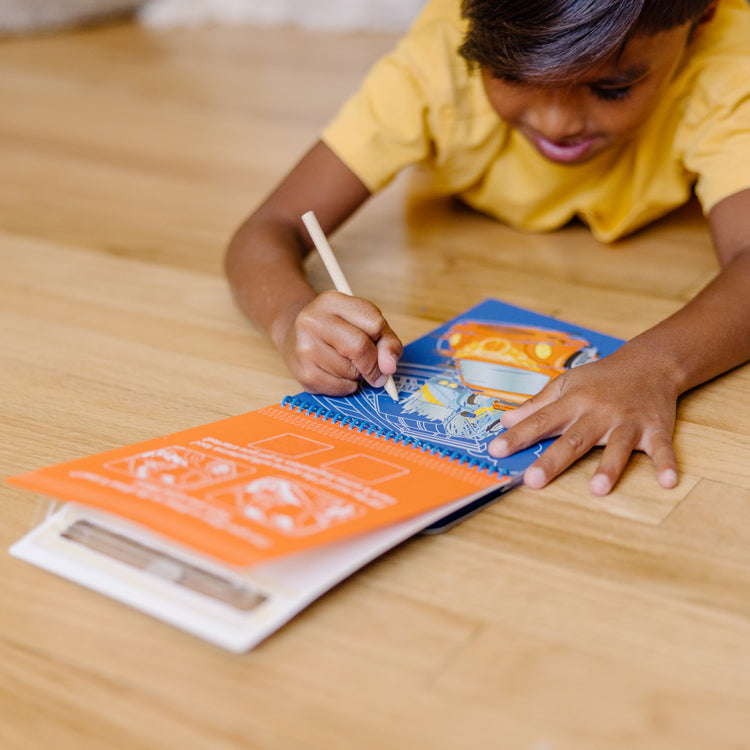 A kid playing with The Melissa & Doug On the Go Scratch Art Color-Reveal Pad - Vehicles