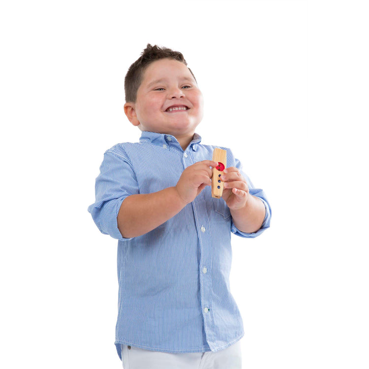 A child on white background with The Melissa & Doug Makin' Music Beginner Wooden Kazoo