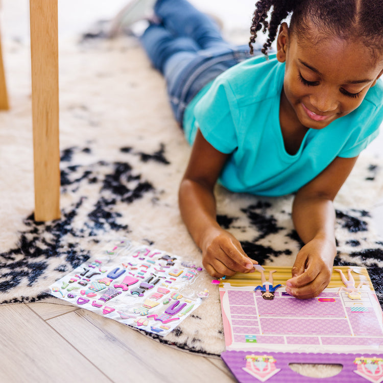 A kid playing with The Melissa & Doug Puffy Sticker Activity Book: Dress-Up - 76 Reusable Stickers