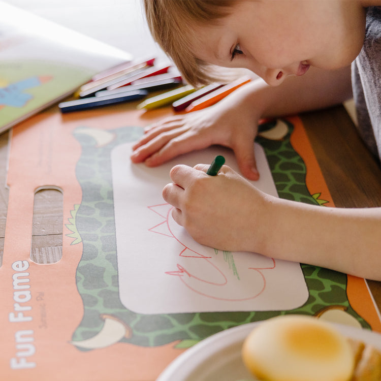 A kid playing with The Melissa & Doug Playmats Dinosaurs Take-Along Paper Coloring And Learning Activity Pads (24 Pages)