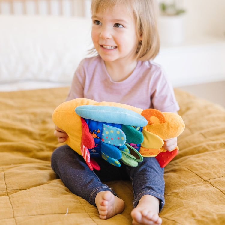 A kid playing with The Melissa & Doug Flip Fish Soft Baby Toy