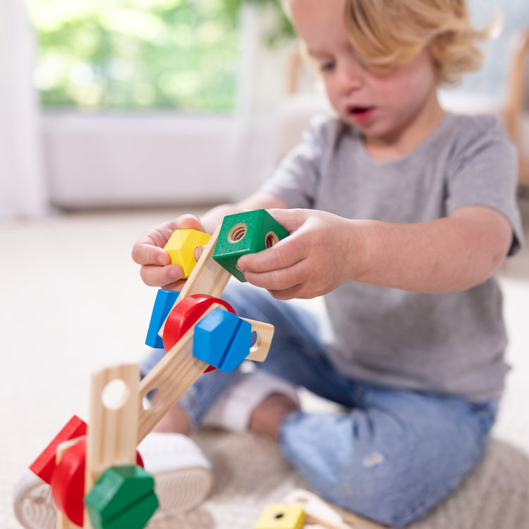 A kid playing with The Melissa & Doug Wooden Construction Building Toy Play Set in a Box, Developmental Educational Toy (48 pcs)