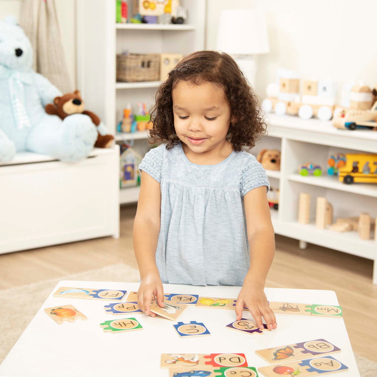 A kid playing with The Melissa & Doug Self-Correcting Alphabet Wooden Puzzles With Storage Box (52 pcs)