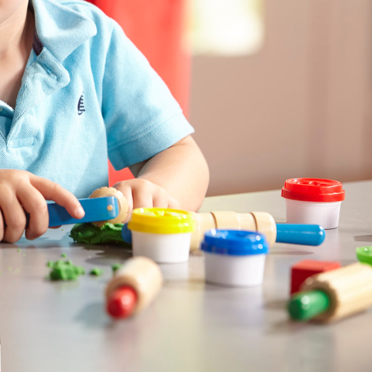 A kid playing with The Melissa & Doug Clay Play Activity Set - With Sculpting Tools and 8 Tubs of Modeling Dough