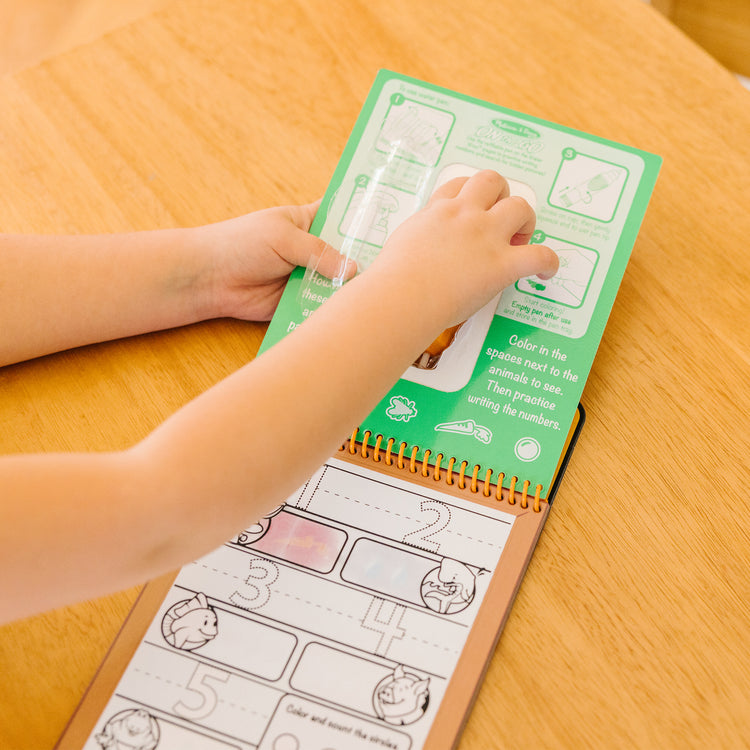 A kid playing with The Melissa & Doug On the Go Water Wow! Reusable Water-Reveal Activity Pad - Numbers