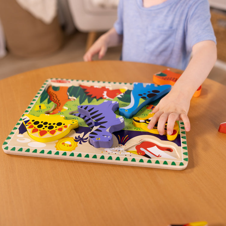 A kid playing with The Melissa & Doug Dinosaur Wooden Chunky Puzzle (7 pcs)