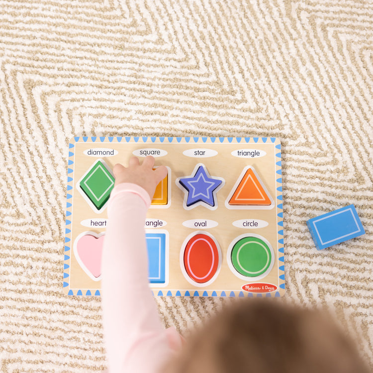 A kid playing with The Melissa & Doug Shapes Wooden Chunky Puzzle (8 pcs)