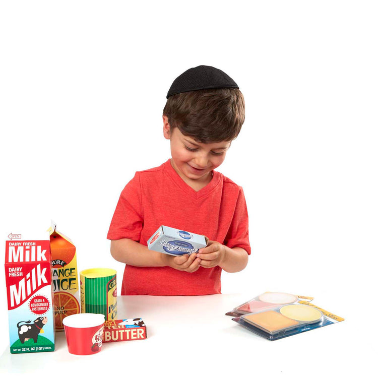 A child on white background with The Melissa & Doug Fridge Groceries Play Food Cartons (8 pieces)