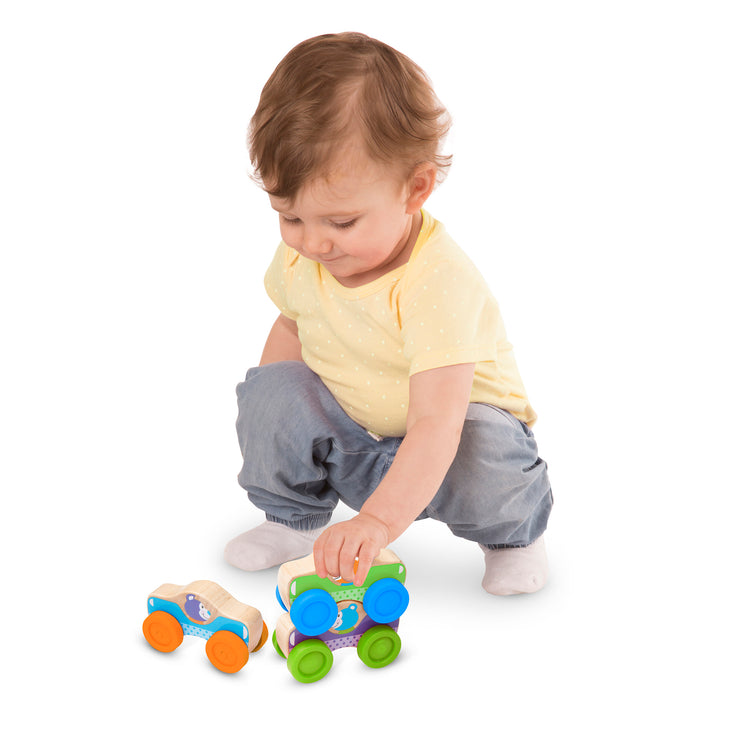 A child on white background with The Melissa & Doug First Play Wooden Animal Stacking Cars (3 pcs)