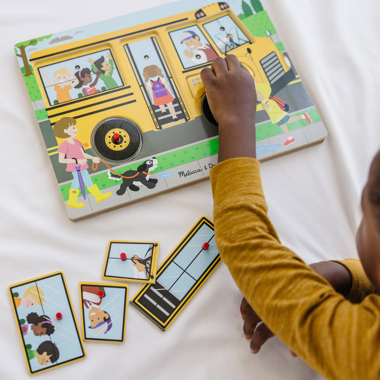 A kid playing with The Melissa & Doug The Wheels on the Bus Sound Puzzle