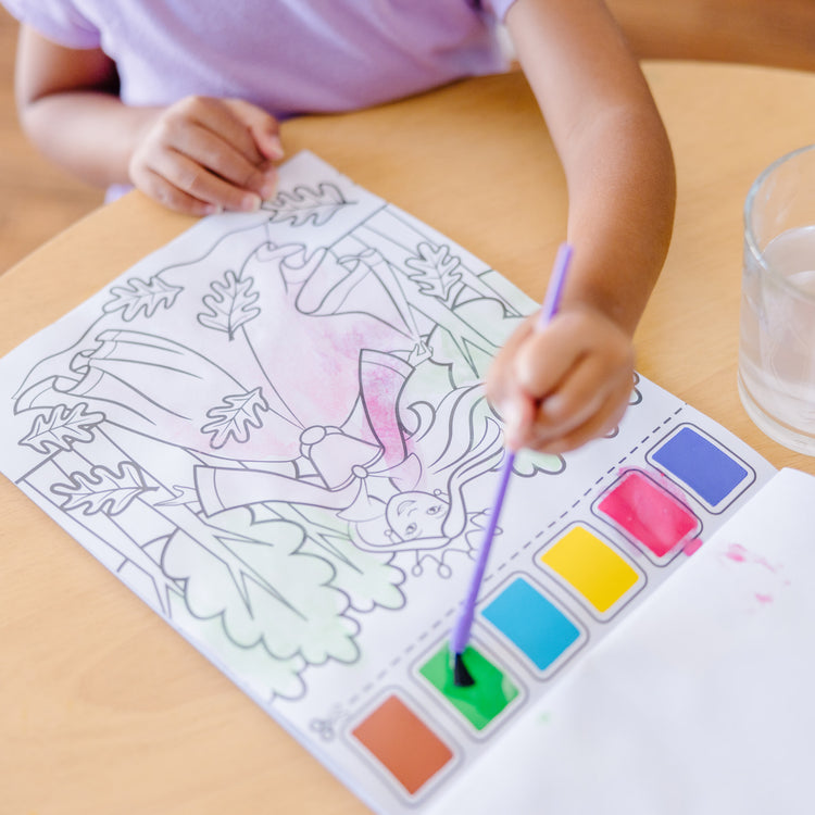 A kid playing with The Melissa & Doug Paint With Water - Princess, 20 Perforated Pages With Spillproof Palettes