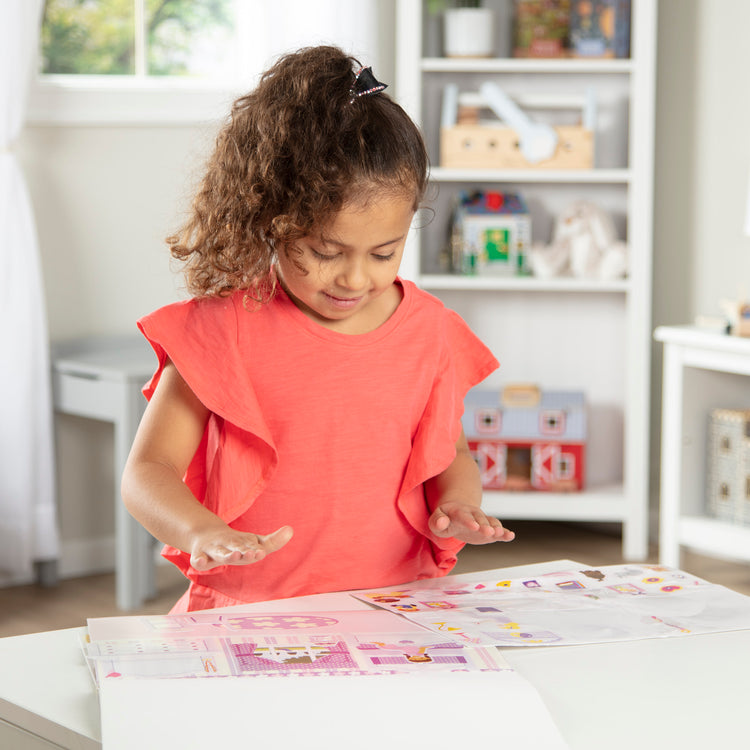 A kid playing with The Melissa & Doug Reusable Sticker Pad Set: Play House - 175+ Reusable Stickers