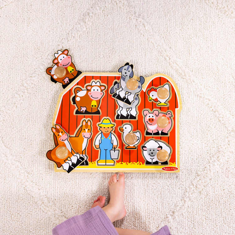 A kid playing with The Melissa & Doug Farm Animals Jumbo Knob Wooden Puzzle