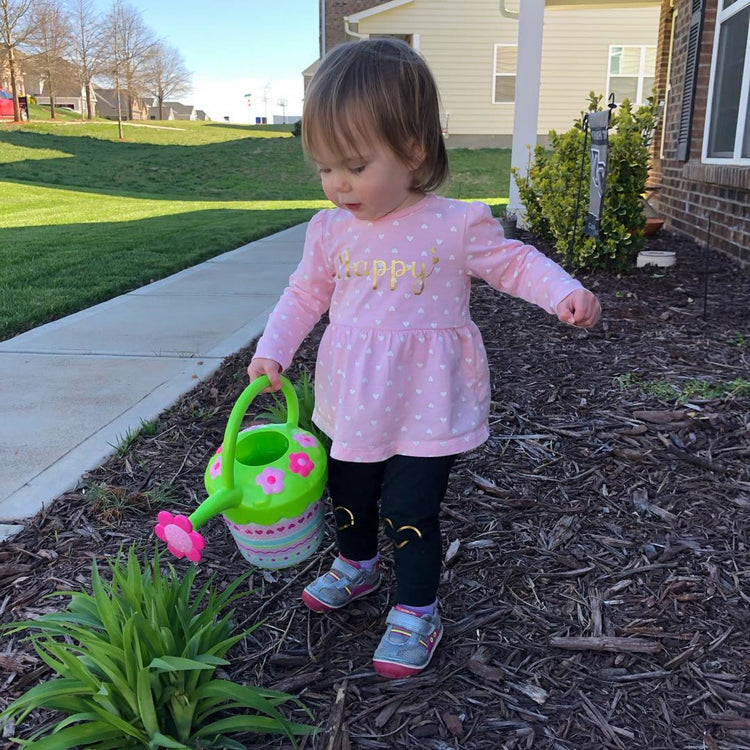 A kid playing with The Melissa & Doug Sunny Patch Pretty Petals Flower Watering Can - Pretend Play Toy