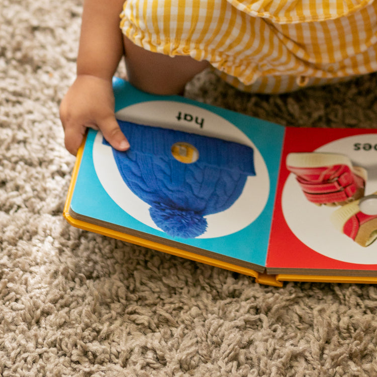 A kid playing with The Melissa & Doug Children’s Book – Poke-a-Dot: First Colors (Board Book with Buttons to Pop)