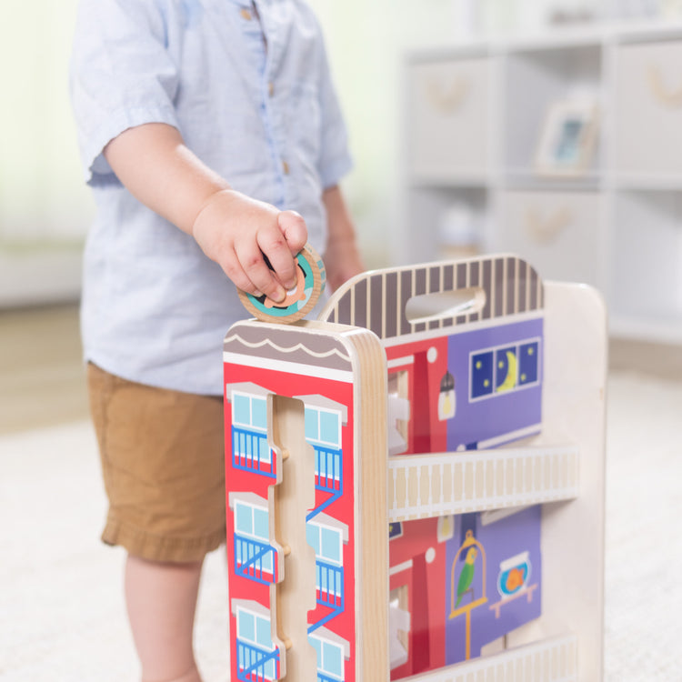 A kid playing with The Melissa & Doug GO Tots Wooden Town House Tumble with 6 Disks