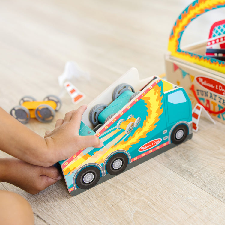 A kid playing with The Melissa & Doug Fun at the Fair! Wooden Ring of Fire Stunt Jumper Cars Game