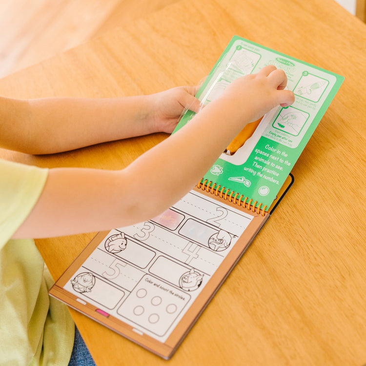 A kid playing with The Melissa & Doug On the Go Water Wow! Reusable Water-Reveal Activity Pad - Numbers