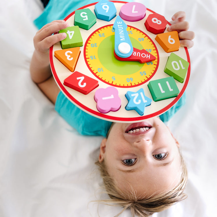 A kid playing with The Melissa & Doug Shape Sorting Clock - Wooden Educational Toy