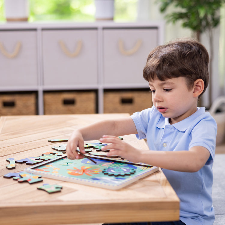 A kid playing with The Melissa & Doug Wooden Underwater Jigsaw Spinning Gear Puzzle – 18 Pieces