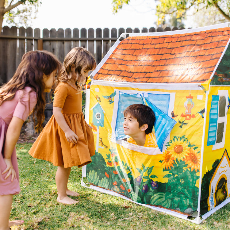 A kid playing with The Melissa & Doug Cozy Cottage Fabric Play Tent and Storage Tote