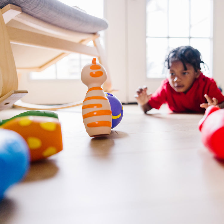 A kid playing with The Melissa & Doug K's Kids Bowling Friends Play Set and Game With 6 Pins and Convenient Carrying Case