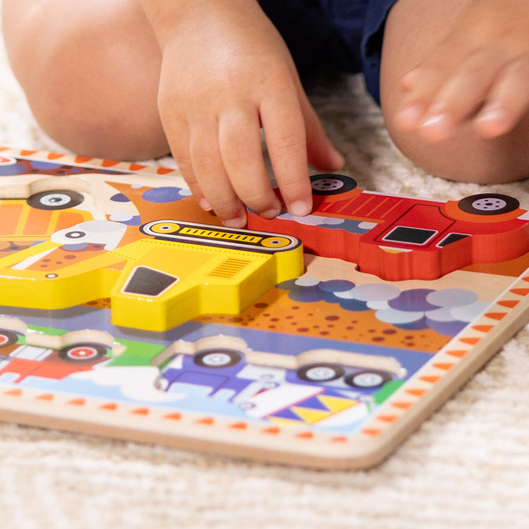 A kid playing with The Melissa & Doug Construction Vehicles Wooden Chunky Puzzle (6 pcs)