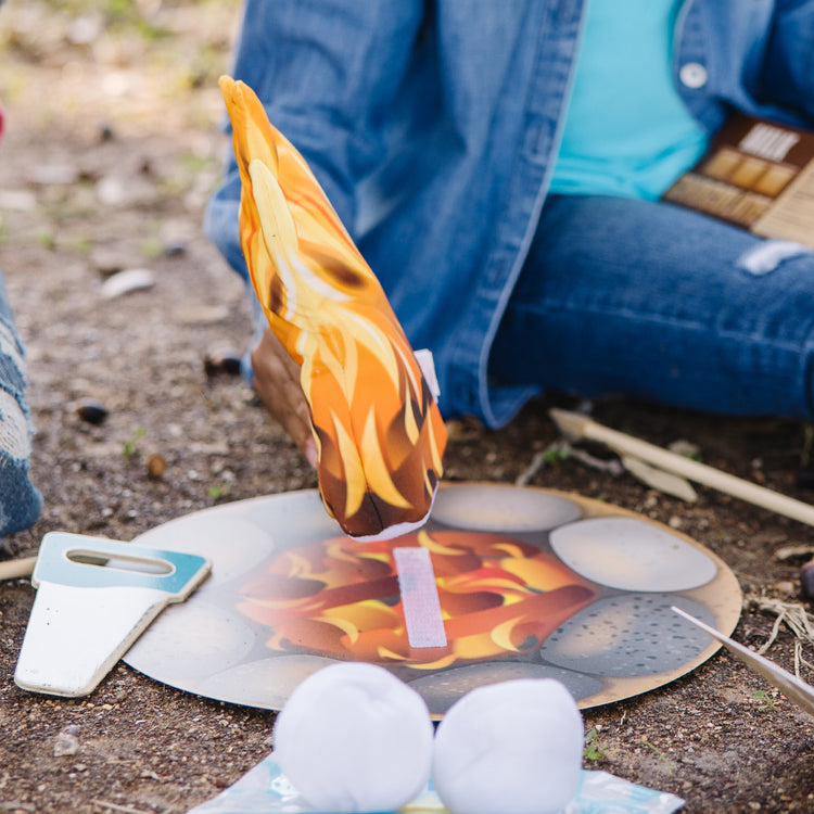 A kid playing with The Melissa & Doug Let's Explore Campfire S'Mores Play Set