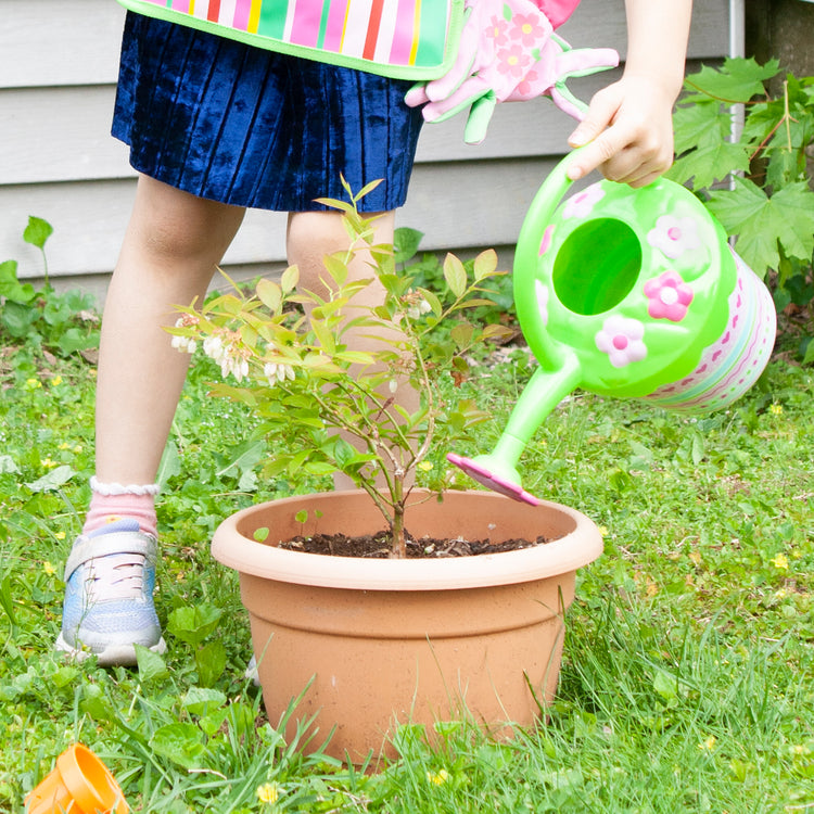 A kid playing with The Melissa & Doug Sunny Patch Pretty Petals Flower Watering Can - Pretend Play Toy