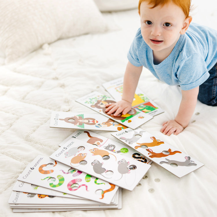 A kid playing with The Melissa & Doug Poke-A-Dot Jumbo Number Learning Cards - 13 Double-Sided Numbers, Shapes, and Colors Cards with Buttons to Pop