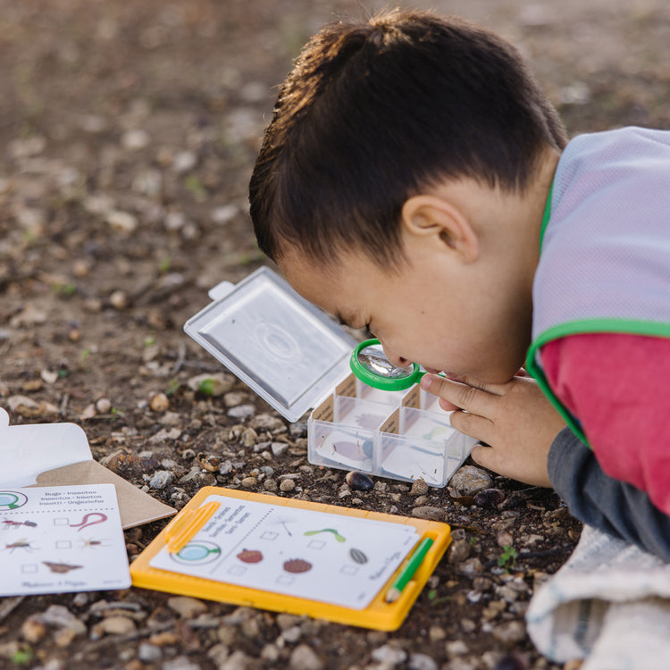 A kid playing with The Melissa & Doug Let’s Explore Naturalist Vest Play Set – 20 Pieces