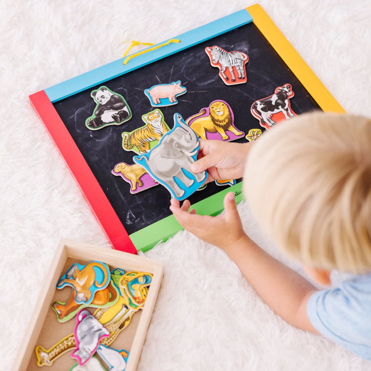 A kid playing with The Melissa & Doug 20 Wooden Animal Magnets in a Box