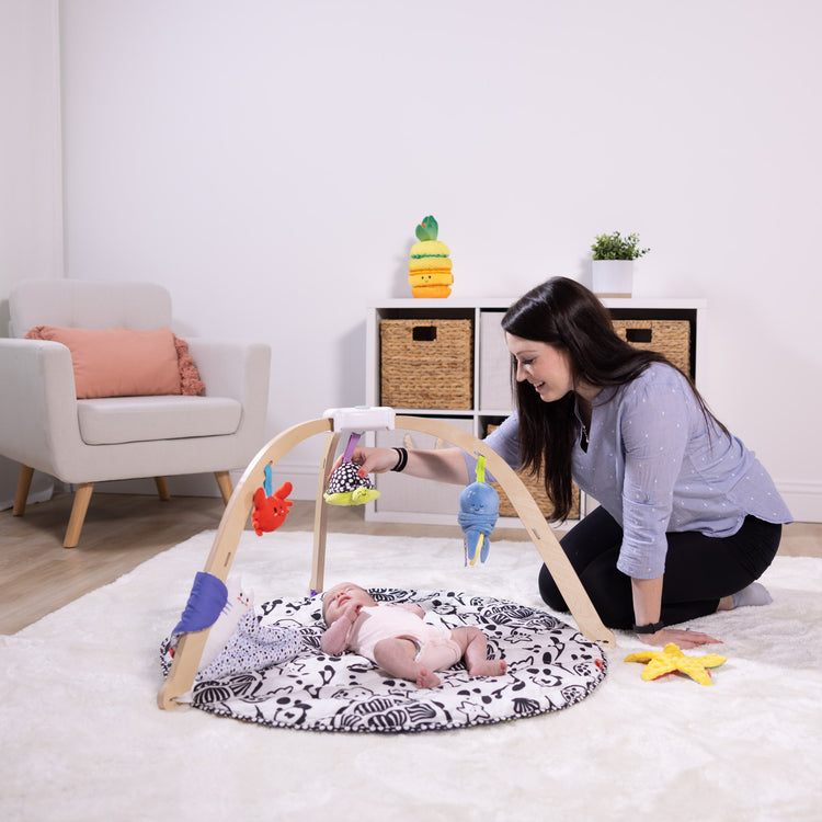 A kid playing with The Melissa & Doug Ocean Easy-Fold Play Gym Developmental Toy for Infants, Reversible Mar, 5 Soft Toys, Birth to 9 Months