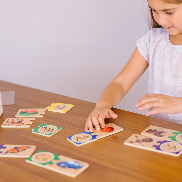 A kid playing with The Melissa & Doug Self-Correcting Alphabet Wooden Puzzles With Storage Box (52 pcs)